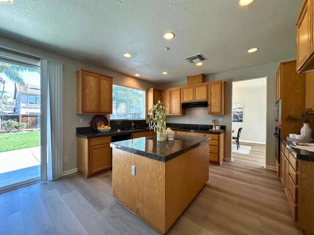 Kitchen featuring a center island, recessed lighting, wood finish cabinets, light wood-style flooring, and a textured ceiling