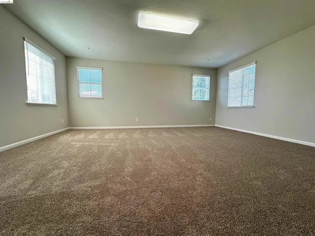 Spare room with dark carpet and a textured ceiling