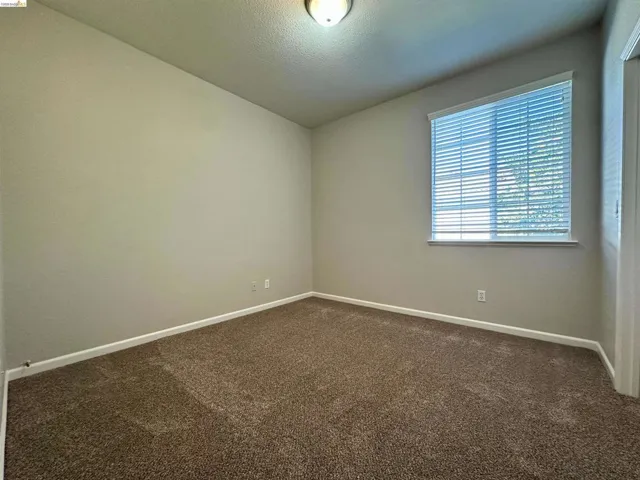 Empty room with dark carpet and a textured ceiling