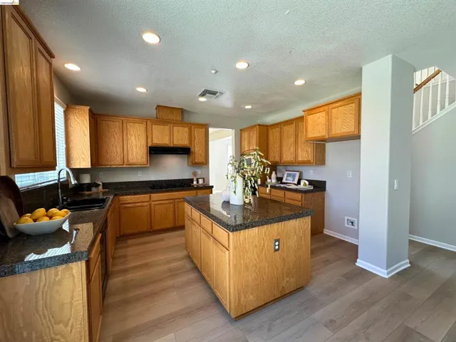 Kitchen with recessed lighting, light wood-style flooring, a center island, wood finish cabinetry, and a textured ceiling