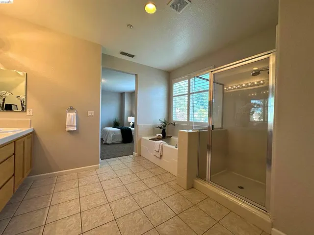 Full bathroom featuring a bath, connected bathroom, vanity, a shower stall, and light tile patterned flooring