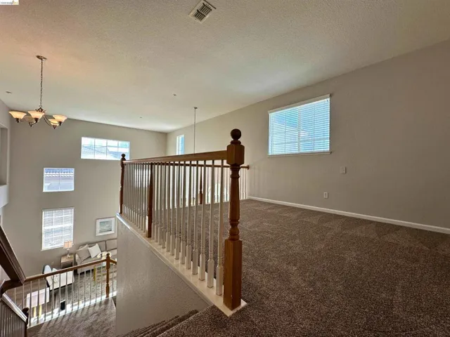 Staircase with suspended lighting, carpet, and a textured ceiling