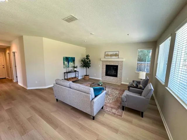 Living room with light wood-type flooring, a tile fireplace, and a textured ceiling