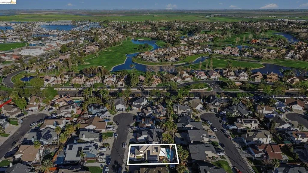 Aerial perspective of suburban area featuring a nearby body of water, property parcel outlined, and a golf course