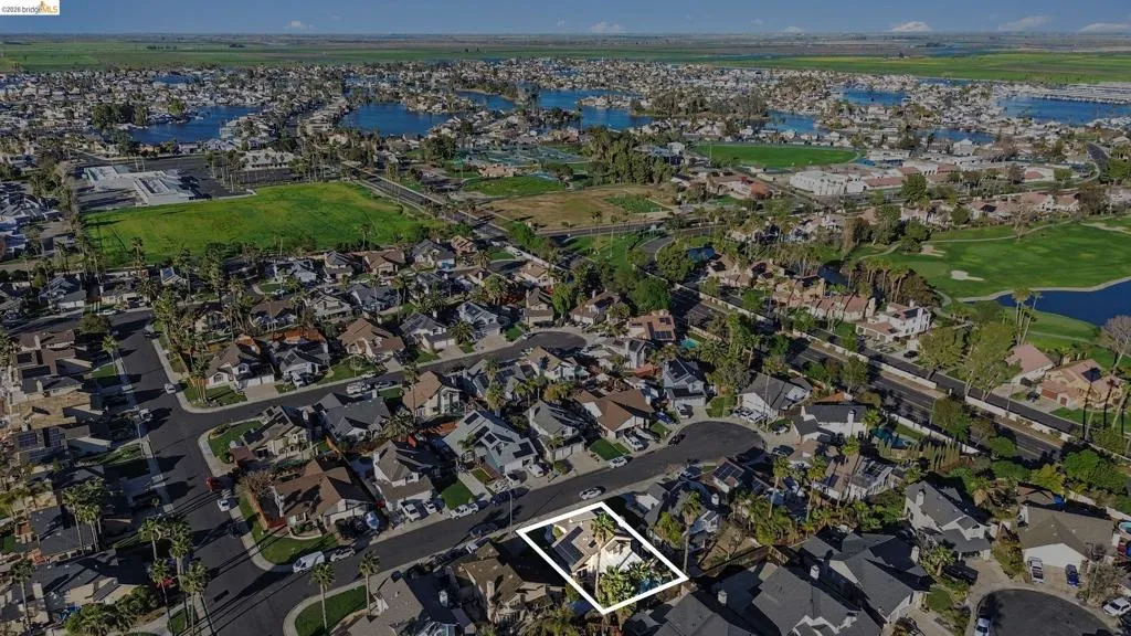 Aerial overview of property's location featuring a nearby body of water, nearby suburban area, and property parcel outlined