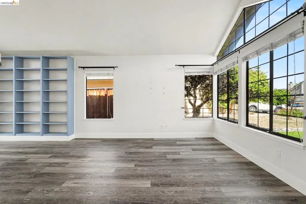 Spacious interior featuring wood-finish flooring, white walls, and built-in shelving