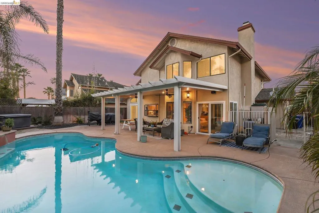 Back of house at dusk with a patio area, stucco siding, a chimney, a fenced backyard, and outdoor furniture