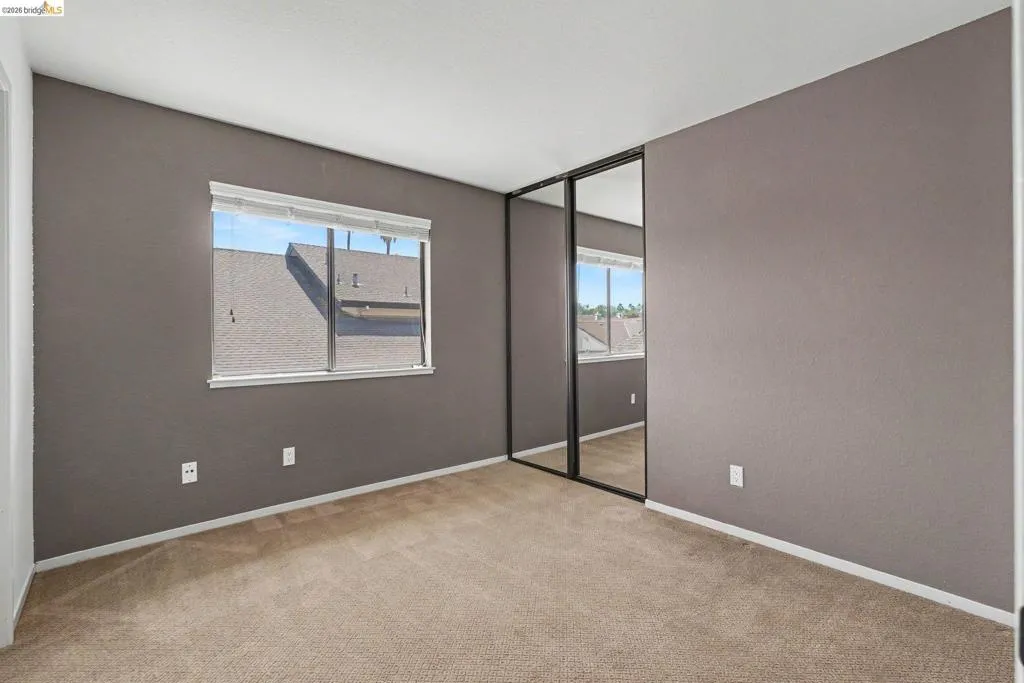 Carpeted room featuring a single window with blinds, painted walls, and a mirrored closet