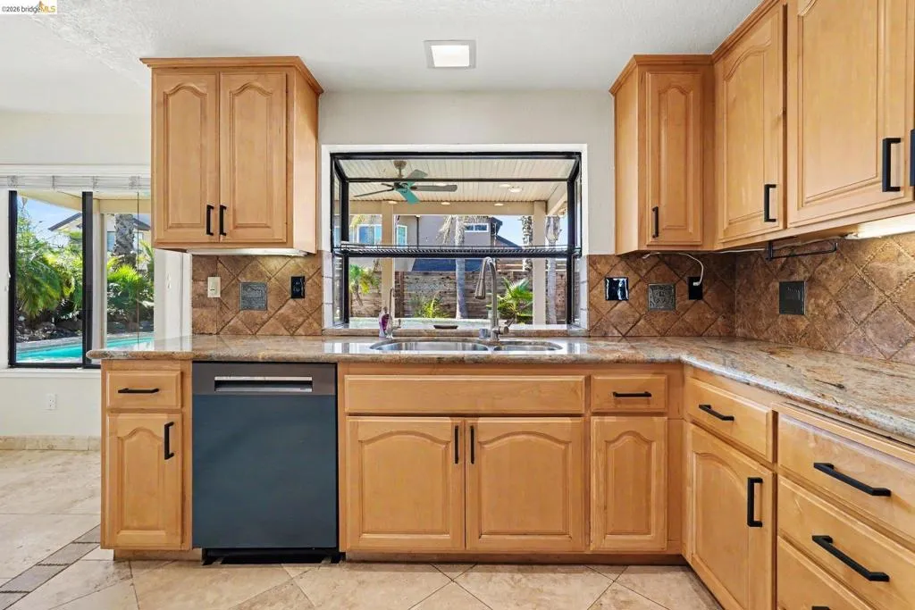Kitchen featuring wood cabinetry with black hardware, granite countertops, and a tiled backsplash