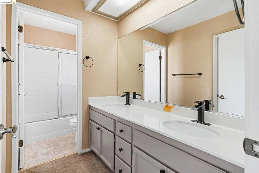 Dual sink vanity with matte black fixtures and a full-width mirror
