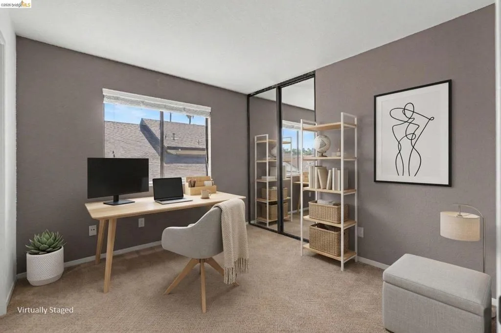 Carpeted room featuring a large window, mirrored closet doors, and light gray walls