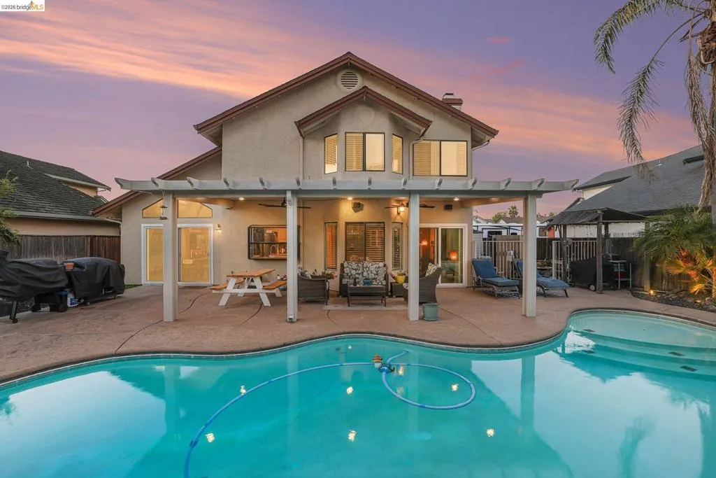 Back of house at dusk featuring a patio area, stucco siding, a fenced backyard, and outdoor seating