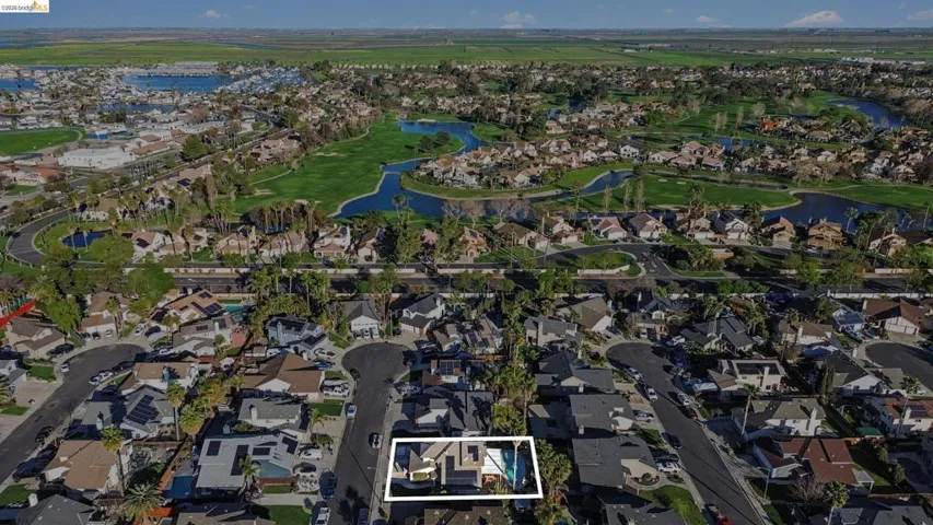 Aerial perspective of suburban area featuring a nearby body of water, property parcel outlined, and a golf course