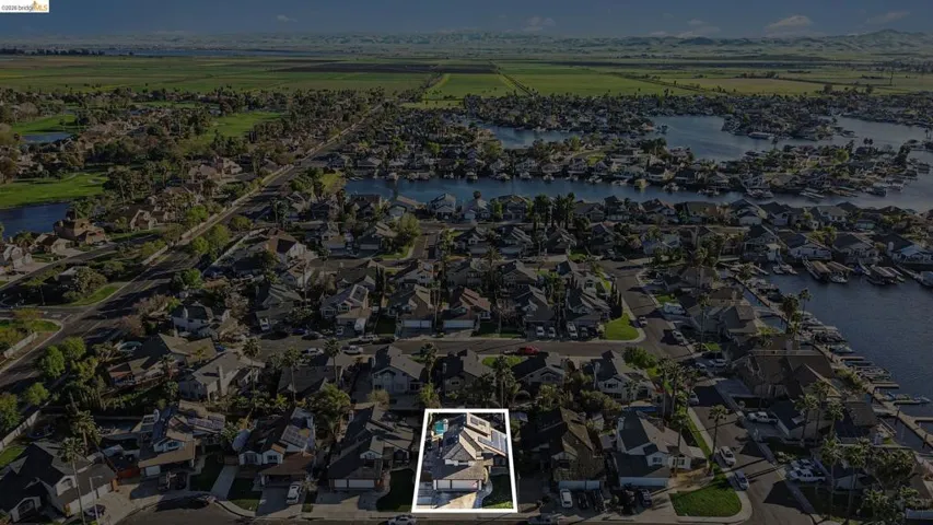 Aerial view of residential area featuring property boundaries highlighted and a nearby body of water