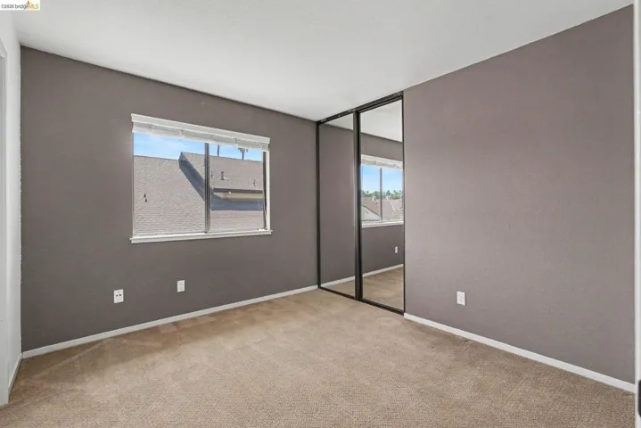 Carpeted room featuring a single window with blinds, painted walls, and a mirrored closet