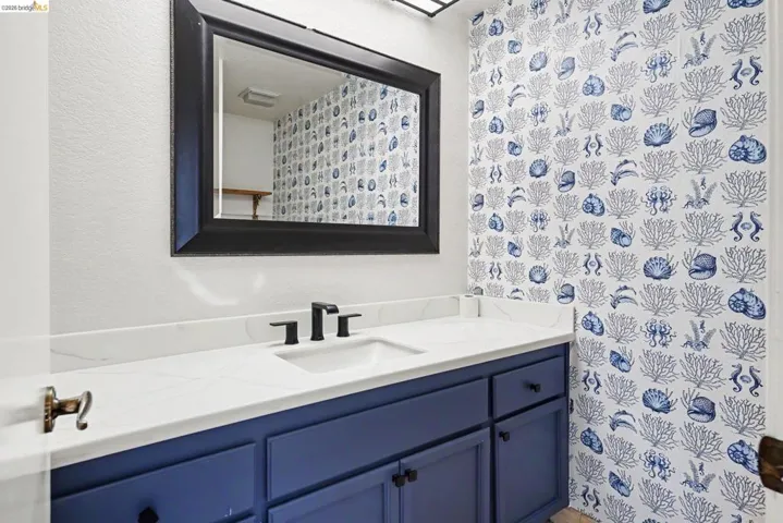 Vanity with a white countertop and integrated sink, matte black faucet, and a large framed mirror