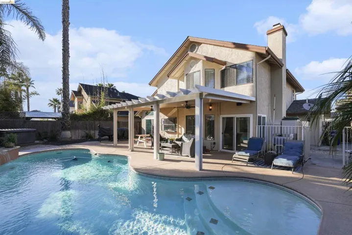 Back of property with a patio area, ceiling fan, a fenced backyard, stucco siding, and a chimney