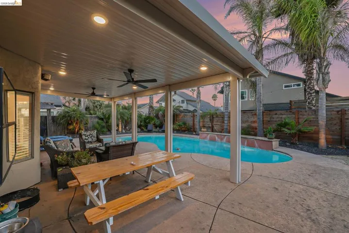 Pool at dusk with a patio, a fenced backyard, and outdoor dining space