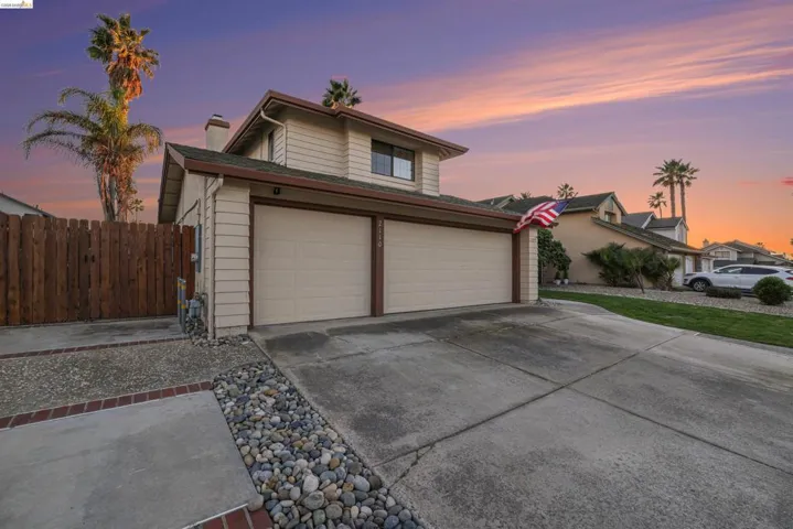 View of front of home with concrete driveway, a chimney, and an attached garage