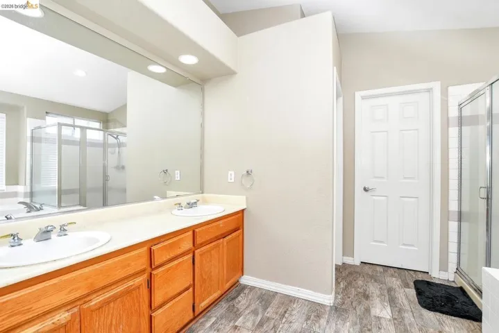 full bathroom featuring a stall shower, double vanity, a bath, light wood-type flooring, and recessed lighting