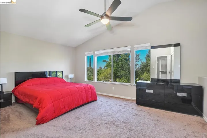 bedroom with carpet flooring, vaulted ceiling, and a ceiling fan