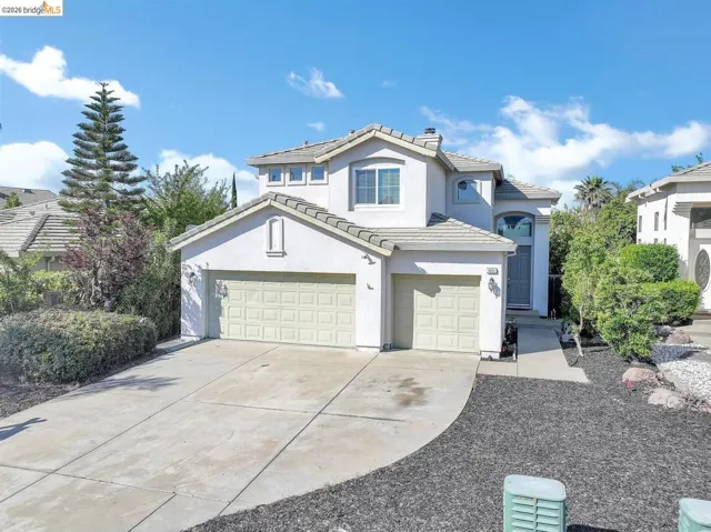 view of front of house with stucco siding, a tile roof, concrete driveway, a garage, and a chimney