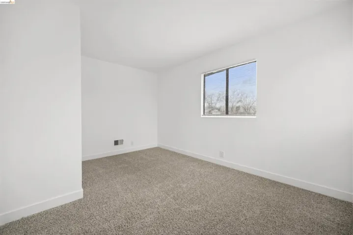 Empty room featuring light colored carpet and baseboards