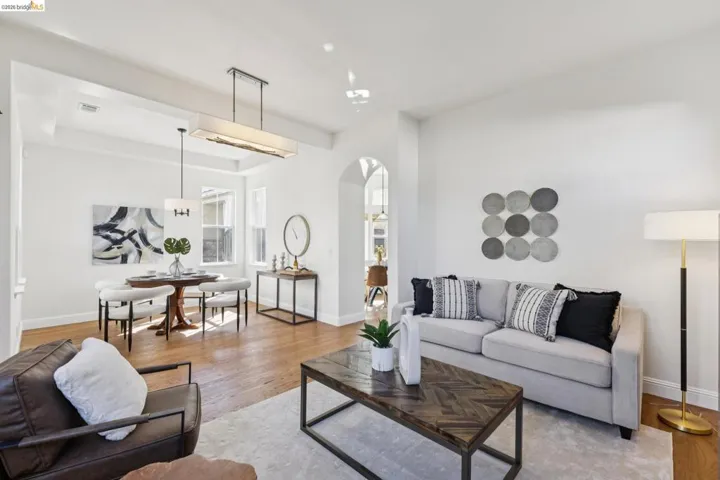 Living room with arched walkways, wood finished floors, and a tray ceiling