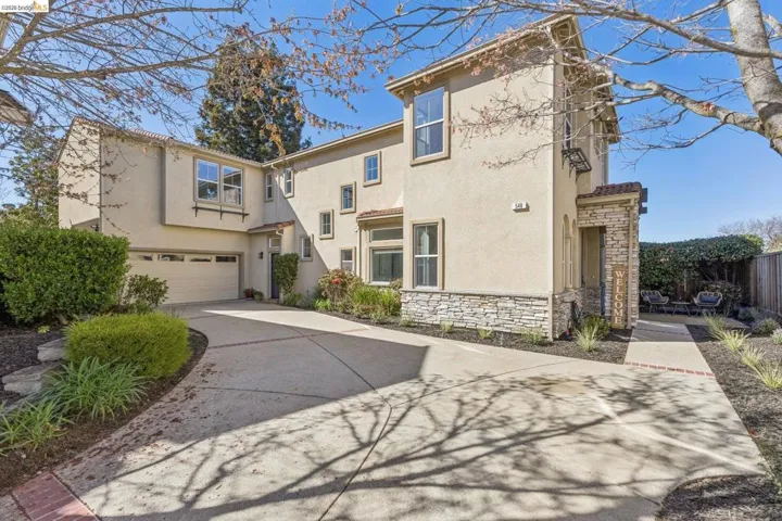 View of front facade with stone siding, stucco siding, driveway, and an attached garage