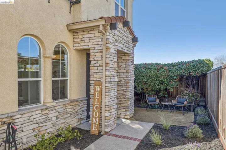 Doorway to property with stone siding, stucco siding, and a patio area