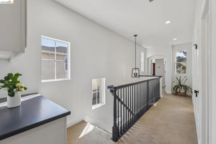 Hall with light carpet, an upstairs landing, recessed lighting, and arched walkways