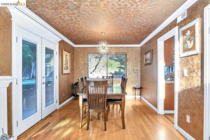 Dining room with light wood finished floors, suspended lighting, and ornamental molding