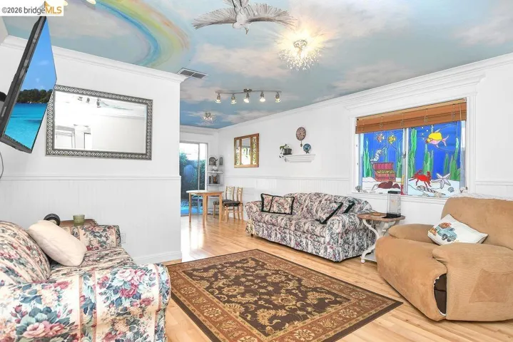 Living area featuring a wainscoted wall, light wood-type flooring, and crown molding