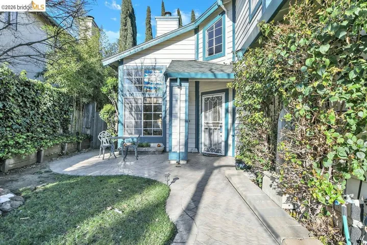View of exterior entry featuring a chimney and a patio