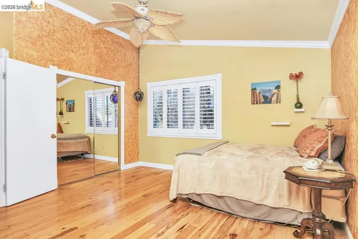 Bedroom with ornamental molding, light wood-type flooring, a closet, ceiling fan, and vaulted ceiling