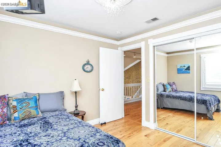 Bedroom with light wood-type flooring, ornamental molding, and a closet