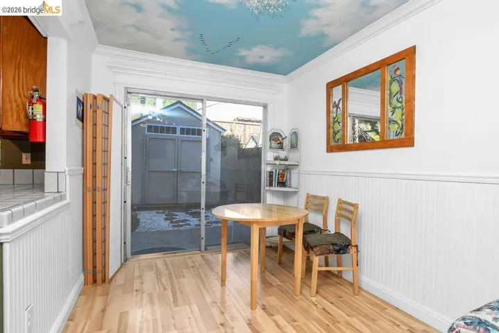 Dining space with light wood-style floors, wainscoting, and crown molding