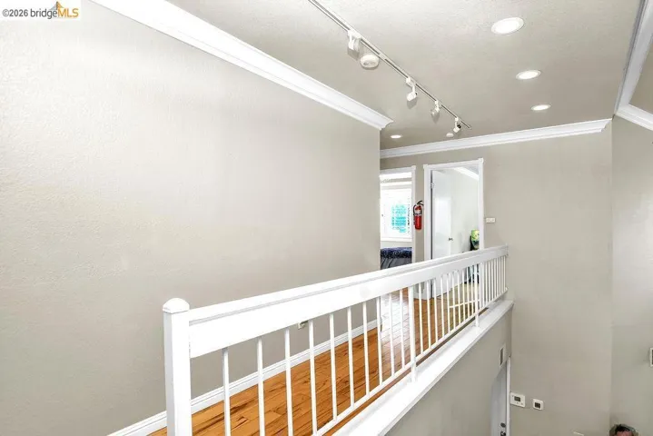 Corridor featuring crown molding, track lighting, and wood finished floors