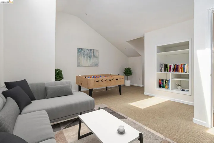 Carpeted living area with built in shelves and lofted ceiling