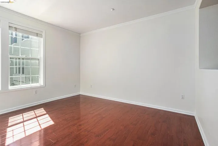 Spare room featuring ornamental molding and dark wood-type flooring