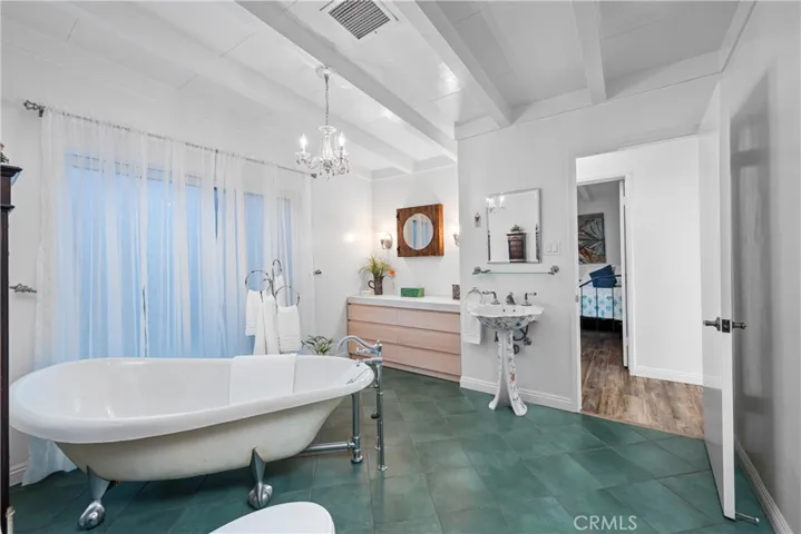 Primary bathroom #1 with soaker tub, beams, and chandelier