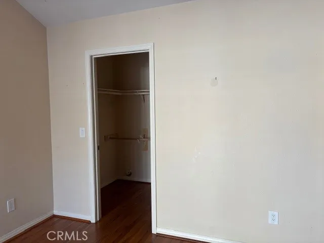 Another view of secondary bedroom/den with wood flooring and walk in closet