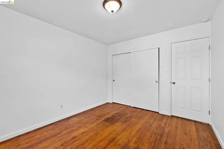 Unfurnished bedroom with dark wood-style floors and a closet