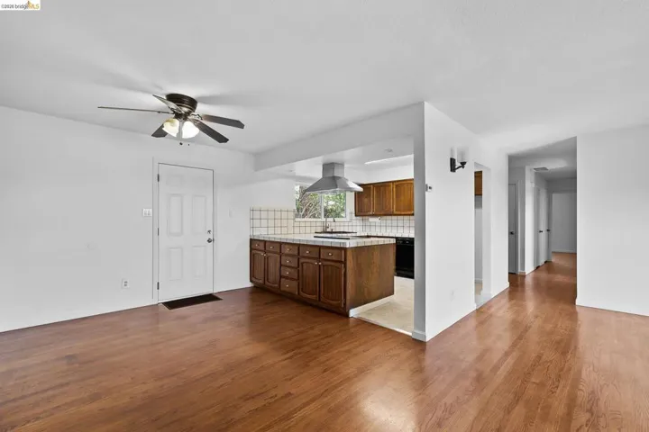 Kitchen featuring tile counters, dark wood-type flooring, tasteful backsplash, ceiling fan, and island range hood