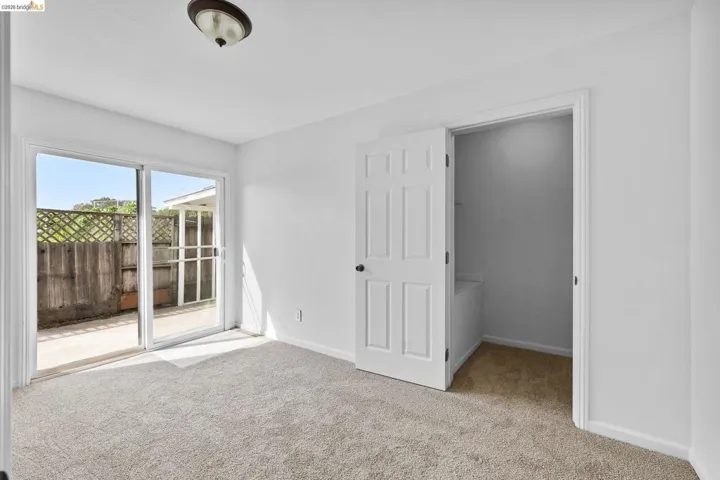 Unfurnished bedroom featuring light colored carpet, access to outside, and a walk in closet