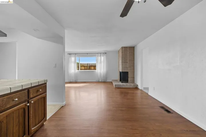 Unfurnished living room featuring light wood-style flooring, ceiling fan, and a fireplace