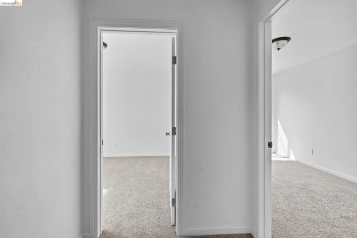 Hall featuring light colored carpet and baseboards