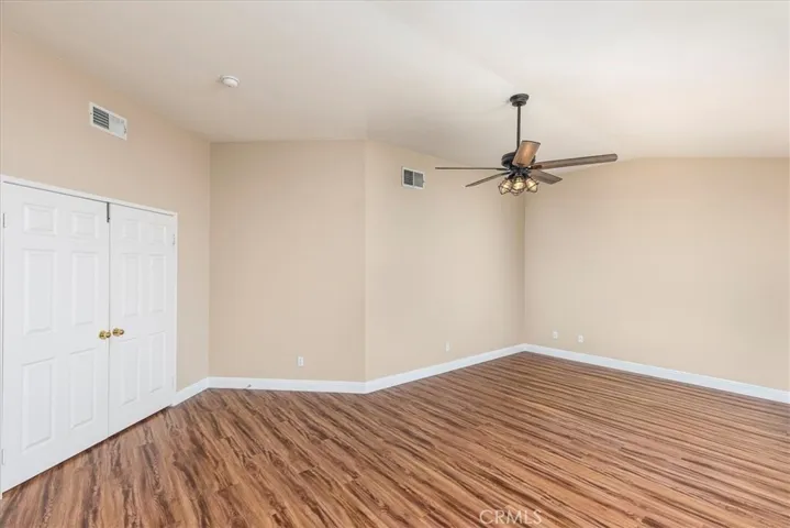 Primary bedroom with double door entry and ceiling fan.  Newer flooring.