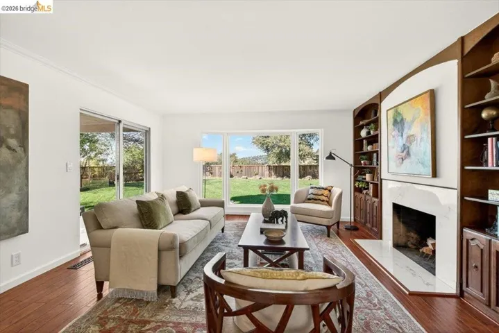 Living area with dark wood-type flooring, a high end fireplace, and built in features