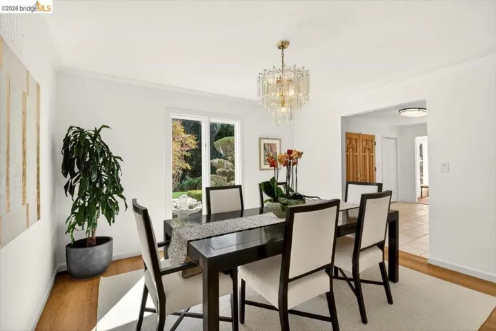 Dining space featuring wood finished floors, a chandelier, and crown molding